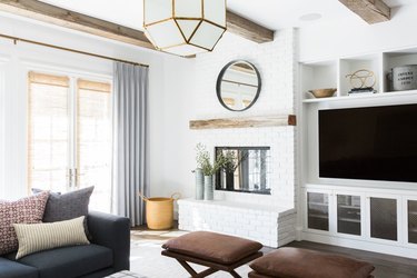 family room with fireplace and TV layout with exposed wood beams and leather ottomans