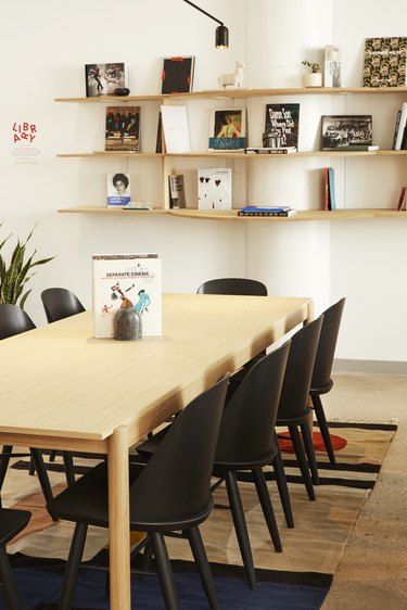 library area with books on shelves, table and black chairs