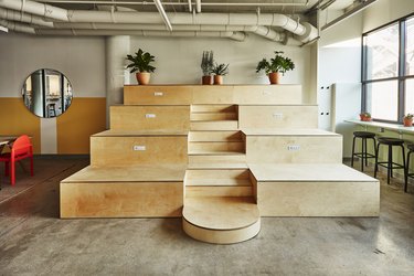 photo of wooden bleachers with planters on top and a round mirror to the left