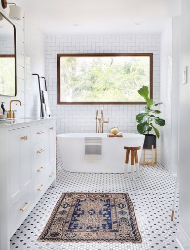 Bathroom fiddle leaf fig near freestanding bathtub and large window