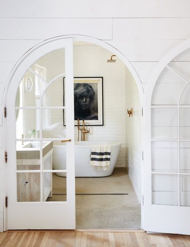 white farmhouse bathroom with freestanding bathtub and black and white artwork