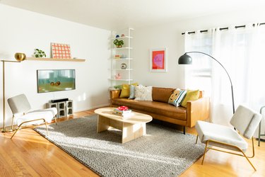 living room with gray rug, leather couch, white walls