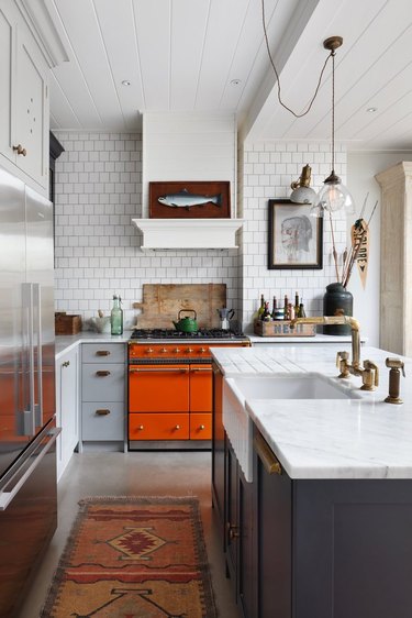 orange kitchen color idea with orange Aga oven and white subway tile backsplash