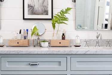 light blue bathroom vanity, grey stone countertop, sink, mirror and shiplap wall