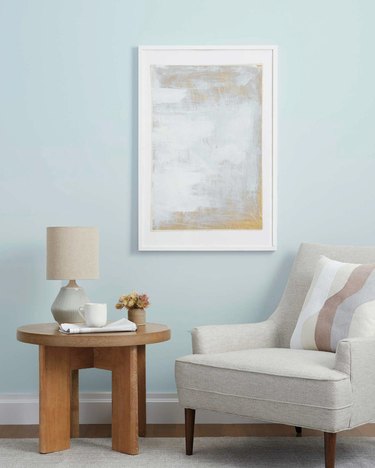 gray chair with wood table and framed artwork on the wall