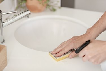 Sponge and spray cleaning bathroom sink