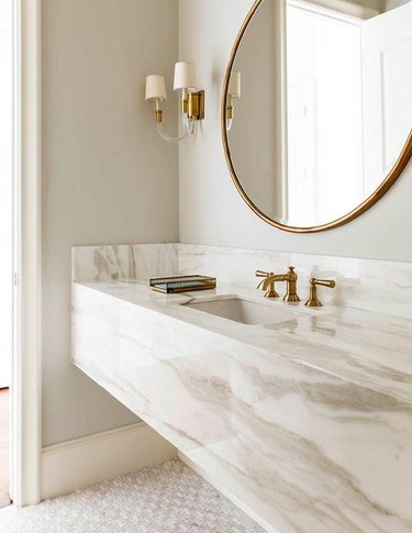 bathroom with marble backsplash and gold hardware