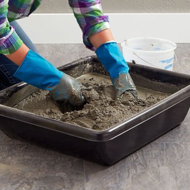 Hand mixing concrete in a tub.