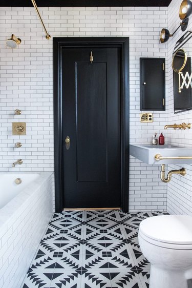 small bathroom lighting idea with wall sconce above vanity and patterned floor tile