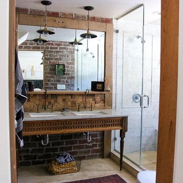 modern farmhouse bathroom with brick walls and rustic vanity with Carrera marble countertop
