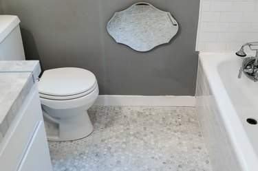mosaic tile bathroom floor, mirror on wall reflecting tile