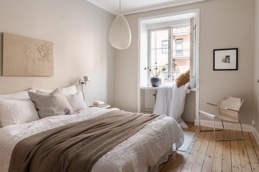 Scandinavian inspired beige bedroom with wood flooring and white trim