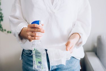 woman holding cleaning spray bottle and paper towel