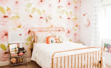 copper bed in pink kids bedroom idea with floral wallpaper and ruffled drapery