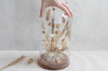 Placing cloche over dried florals