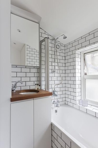 small white bathroom with subway tile walls and wood countertop