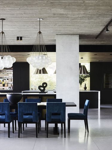 concrete kitchen flooring in modern kitchen with blue velvet dining chairs