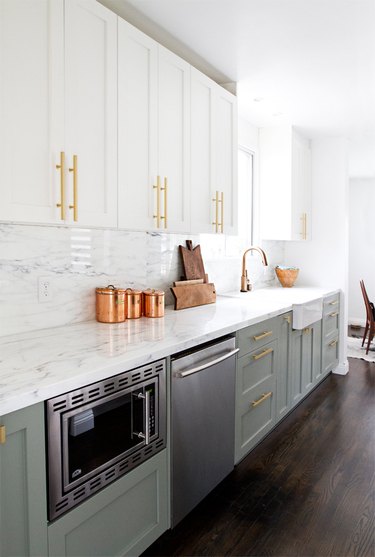 two-tone kitchen cabinets with white and light green and brass pulls