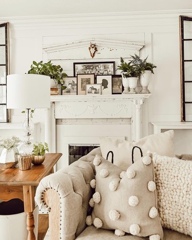 all white farmhouse mantel decorating idea in the living room with tufted sofa
