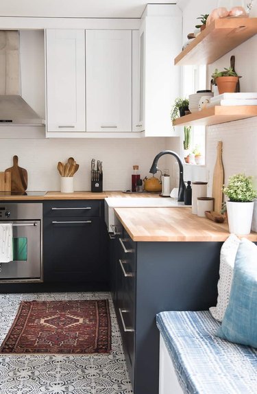 two-tone kitchen cabinets with white and navy blue and patterned floor tile and butcher block countertops