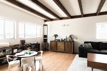 living room with hardwood flooring, white walls, hardwood beams across ceiling