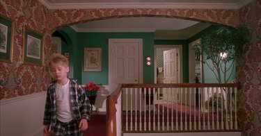 young boy walking down the stairs in christmas-colored home, still image from home alone set