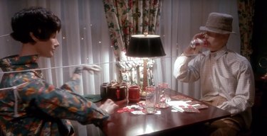 mannequins pretending to drink and play cards at table, still image from home alone set