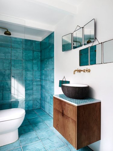 Blue tile on the floor and wall of this master bathroom with modern sink.