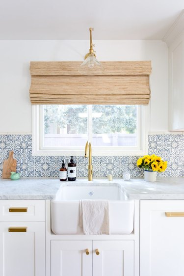 Blue and white Moroccan tile backsplash with apron front sink and white cabinets