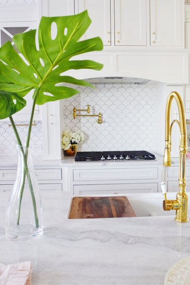 White fish scale Moroccan tile backsplash with marble countertop and white cabinets