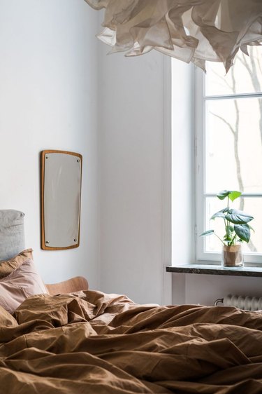 rumpled rust-orange hued  linen sheets in moody bedroom