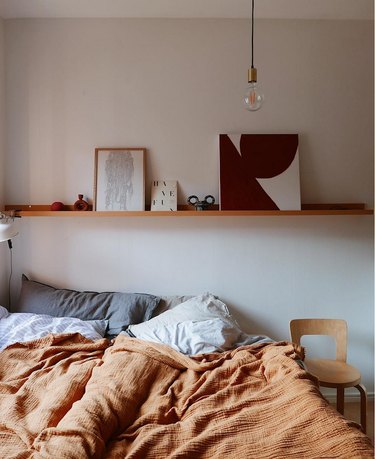 bedroom with orange blanket and warm wood accents