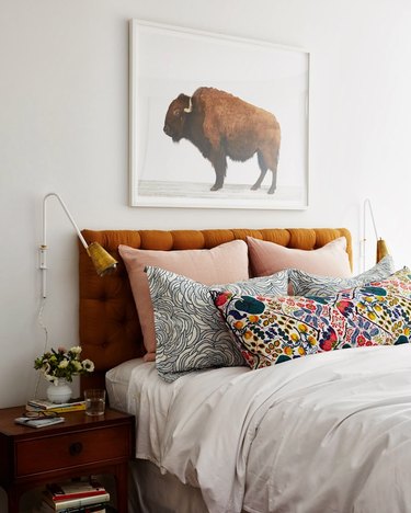 bedroom makeover with tufted orange headboard flanked by wallsconces