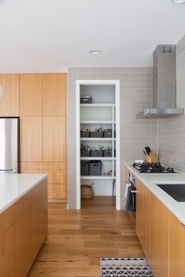 galley style kitchen with view of industrial kitchen vent and hardwood floors