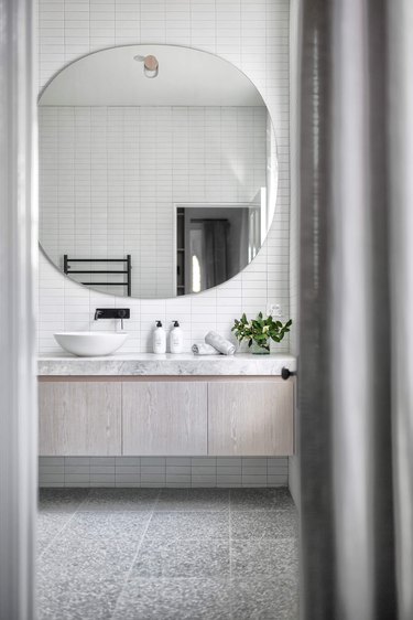 gray contemporary bathroom with floating vanity and large round mirror