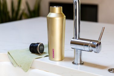 Water bottle near sink faucet and dish towel