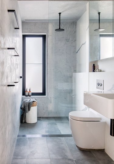 Modern bathroom with black fixtures, frameless shower door, and light gray floor tile.