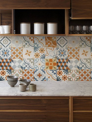 Orange, blue, and white Mexican tile backsplash in varying patterns with wood cabinetry
