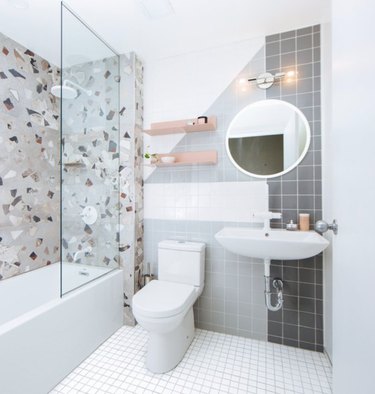 Terrazzo tile shower walls with while bathroom floor tiles and frameless shower door.