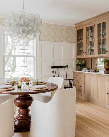 tall dining room wainscoting in farmhouse with floral wallpaper and built-in cabinetry