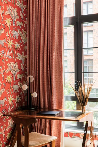 red home office wallpaper with matching window treatments, a desk pushed against the window