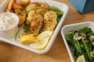 Macadamia-crusted fish sticks, sweet potato wedges, and roasted broccolini with garlic at the Village Den restaurant in NYC.