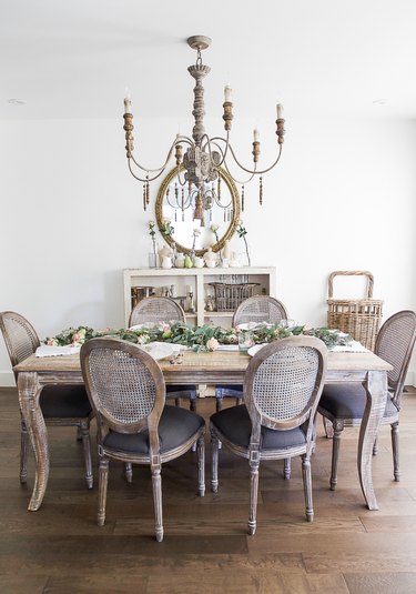 French country dining room with vintage style chairs and distressed table with chandelier above