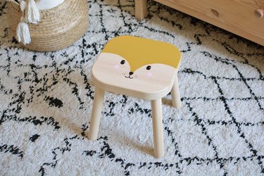 IKEA stool painted with an animal face in bedroom.