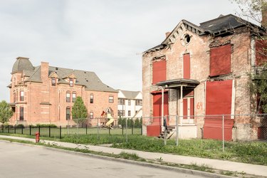 large red brick home with playground next to abandoned home with boarded windows