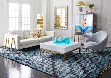 living room space with white couch, gray chair, and white coffee table with gold legs