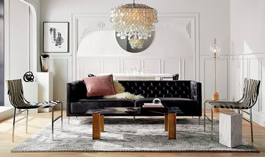 living room with black sofa, chandelier and two chairs