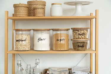 Bookshelf pantry with glass containers and baskets.