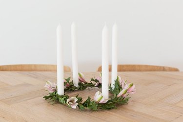 Floral and candle centerpiece on wood dining table.