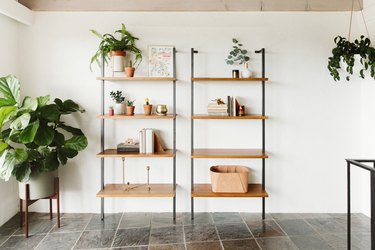 focus on open bookshelves in a tiled room with plants